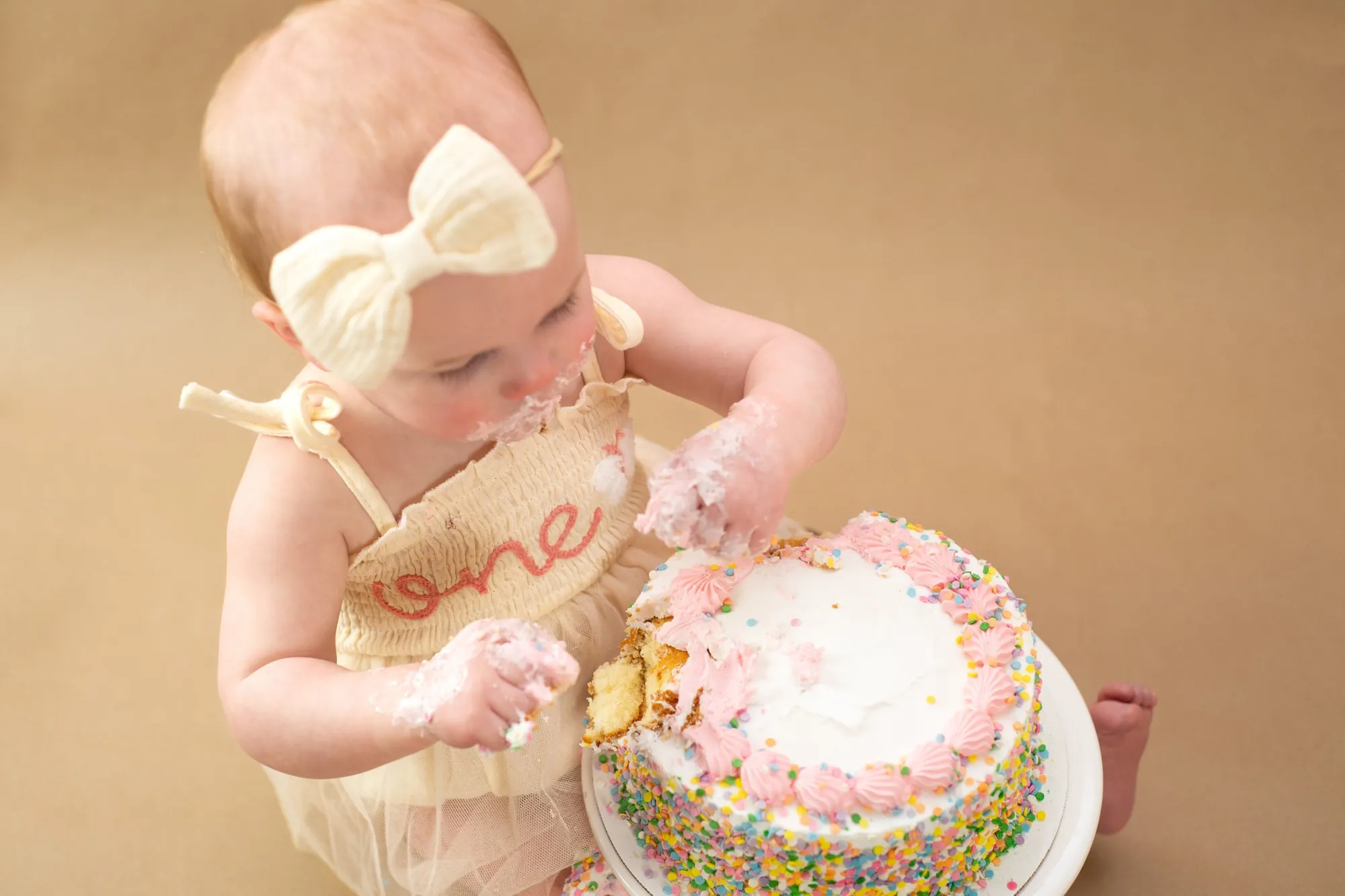 Cake smash photos in the Cedar Valley, messy frosting hands on her first birthday